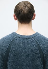 Blauer pullover mit strukturiertem Material, rundem Halsausschnitt und RaglanÄrmeln. Besteht aus weichem Stoff und weist ein auffälliges, erhabenes Muster auf der Oberfläche auf.