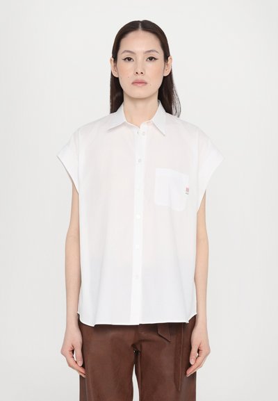 Camisa blanca de botonadura corta con mangas cortas y un bolsillo. Fabricada en una tela suave, cuenta con un cuello sencillo y un pequeño acento a rayas en el bolsillo.