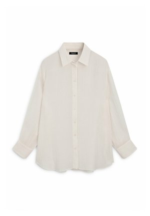 Chemise blanche à manches longues avec col pointu et poignets, réalisée en tissu léger et texturé.