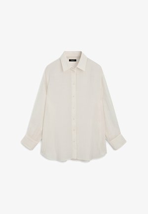 Chemise blanche à manches longues avec col pointu et poignets, réalisée en tissu léger et texturé.