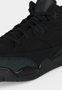 Μαύρο sneaker ψηλού τύπου με υφή στη σόλα, επένδυση στον γιακά και ορατά κορδόνια, που δείχνει κοντινή λήψη των εμπρόσθιων και πλαϊνών λεπτομερειών.