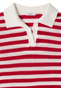 Polo en maille blanc avec des rayures horizontales rouges et un petit col, avec une étiquette de marque "CECIL" au niveau de l'encolure.
