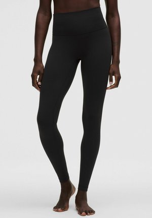 Højtaljede sorte leggings lavet af elastisk materiale, med en glat tekstur og et tætsiddende design, der fremhæver kropsformen.