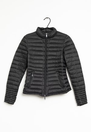 Schwarze gesteppte Steppjacke mit Stehkragen, Frontreißverschluss, zwei Reißverschlusstaschen, auf einem schwarzen Bügel vor weißem Hintergrund gezeigt.