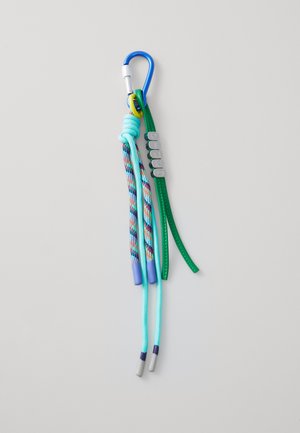 Blue carabiner holds multi-colored cords and a green strap with silver beads spelling "PINKO" against a light gray background.