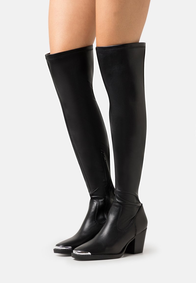 Bottes noires en cuir, au-dessus du genou, avec un bout rond, un talon haut en bloc et des accents métalliques sur le bout. Comprend une fermeture éclair sur le côté pour un enfilage facile.