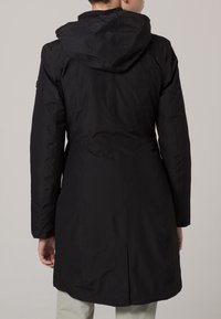 Manteau noir long à capuche avec une texture lisse. Présente une taille cintrée et un ourlet légèrement évasé. Design simple, sans éléments métalliques visibles.