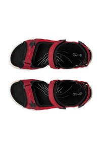 Punaiset ja mustat avoimilla varpailla varustetut sandaalit, joissa säädettävät remmit, pehmustetut pohjalliset ja valkoiset pohjat, nähtynä ylhäältä.