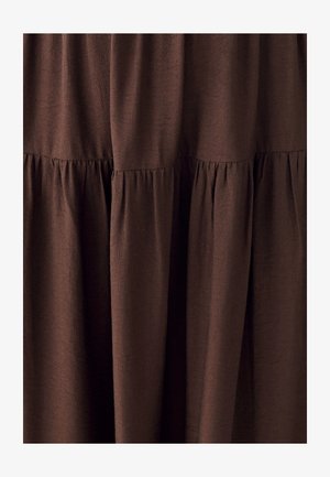 Tumepruun kangas, millel on kogutud, kihilised õmblused, mis loovad pehmeid voldikesi ja tekstuurse, kihilise välimuse.