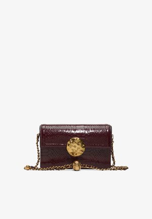 Donkerrode lakleren clutch met krokodillenstructuur, voorzien van een grote goudkleurige, gehamerde ronde sluiting en een gouden kettingband.