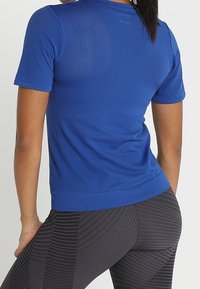 Camiseta de rendimiento de manga corta en azul brillante, con un diseño de malla transpirable, textura suave y silueta ajustada.