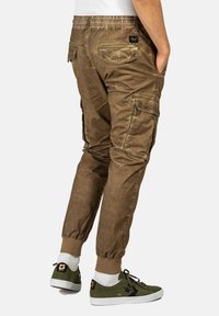 Cargohosen in einem verblassten olivgrün, mit elastischem Bund, schmal zulaufendem Bein, Nähdetails und mehreren Taschen.