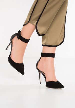 Black high-heeled shoes made of suede with a pointed toe and ankle strap. Features a sleek design and a stiletto heel.