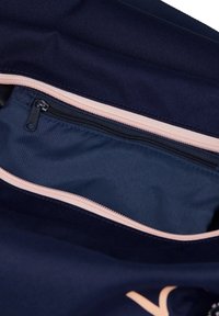 Innenseite einer marineblauen Stofftasche mit einer hellrosa Reißverschlusstasche, die eine glatte Textur und ein kontrastierendes marineblaues Futter aufweist.