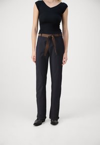 Ναυτικά παντελόνια με πλεκτή καφέ ζώνη που διαθέτει σχέδιο ζιγκ-ζαγκ; ευθεία γραμμή, ελαφρύ ύφασμα, συνδυάζονται με μαύρα παπούτσια.