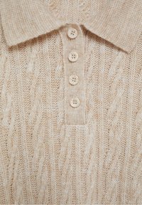 Pull en tricot beige avec un motif en relief, doté d'un col et de quatre boutons crème sur le devant.