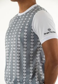 Camisa atlética de manga corta con un diseño de rayas en gris y blanco y un patrón de logotipos repetido; textura suave; logotipo en la manga.