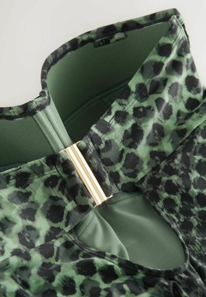 Groen-zwart luipaardprint stof met een gouden hardware accent bij de halslijn. Soepele textuur, aansluitend ontwerp en gestructureerde vorm.