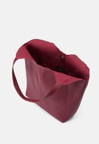 Burgundyröd shoppingväska med en slät utsida, öppen topp med tryckknappsstängning och en foder av tyg inuti. Tunna, stabila handtag ingår.