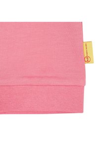Tessuto di cotone rosa con una trama a coste, dotato di un'etichetta gialla con testo. Superficie liscia e design semplice senza motivi visibili.