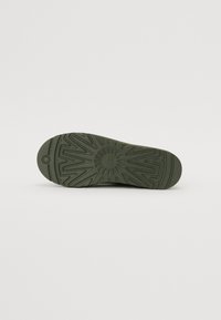 Semelle de chaussure en caoutchouc vert avec un design de bande de roulement à motifs comprenant des éléments en zigzag et circulaires, texture lisse et bout arrondi.