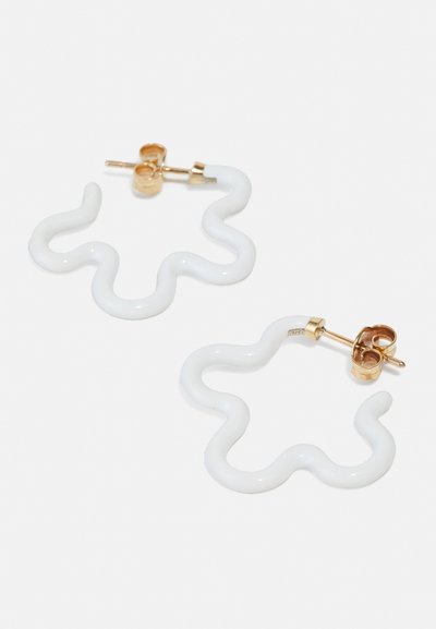 Bijele, valovite naušnice napravljene od sjajnog materijala s zlatnim okovom. Imaju mehanizam za zatvaranje koji osigurava sigurno nošenje.