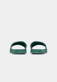 Pantofole verdi in gomma con design a punta aperta, caratterizzate da una forma sagomata e una suola testurizzata per una presa ottimale. Costruzione minimalista e senza cuciture.