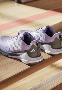 Purple athletic shoes with textured mesh upper, white three-stripe logo, padded collar, and gray accents. Slim, modern design.