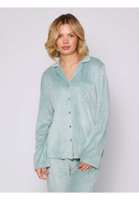 Conjunto de pijama de terciopelo en suave verde menta, que incluye una camisa abotonada con cuello, bolsillo delantero y mangas largas; textura suave.