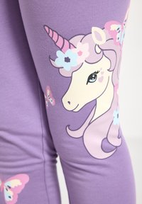 Lilla leggings med enhjørningemotiv, pinkt horn, blomsterdetaljer i blå og pink samt sommerfugle på den nederste del af benet.