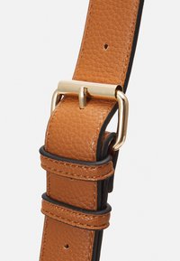 Ceinture en cuir tan avec une finition texturée, dotée de garnitures en métal doré et d'accents noirs. Trois trous réglables pour s'adapter à la taille.