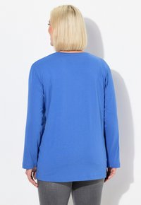 Camicia blu a maniche lunghe realizzata in tessuto morbido, caratterizzata da un orlo dritto e una vestibilità comoda. Design minimale senza motivi o accenti visibili.