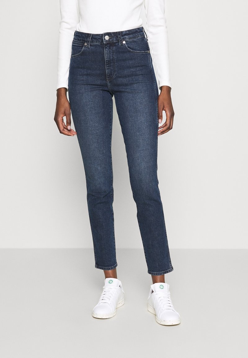 Donkerblauwe high-waisted jeans met een slim fit, voorzien van klassieke vijf-pocket stylen, contrasterende stiksels en een zachte denimtextuur.