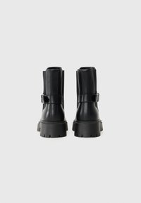 Sorte lær ankle støvler med en kraftig høj sål, med en sidelæderrem og spænde detalje, glat tekstur og rund tå design.