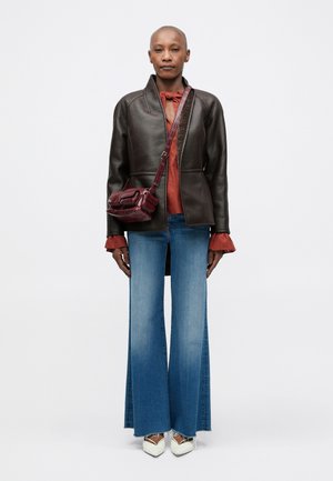 Veste en cuir marron, haut bordeaux avec un détail de nœud, jeans évasés bleu clair, chaussures blanches pointues, petit sac bandoulière bordeaux.