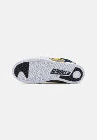 Sneaker with a textured white rubber sole featuring a black and yellow accent, a rounded toe, and a detailed geometric pattern on the bottom.