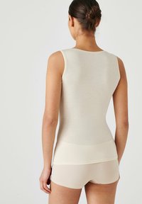 Light beige tank top with a fitted design, round neckline, and ribbed texture, paired with matching briefs. Seamless construction, minimal detailing.