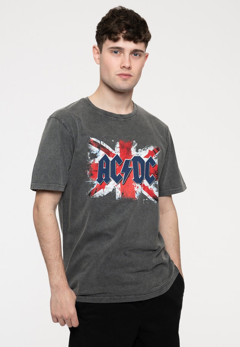 Gray cotton t-shirt featuring a distressed Union Jack design with "AC/DC" in bold blue letters and lightning bolt accent. Short sleeves.