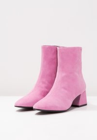 Rosa mocka ank stövlar med spetsig tå och blockklack. Har en slät yta och en sidodragkedja för stängning.