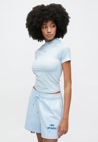 Αθλητική μπλούζα ανοιχτού γαλάζιου με κοντά μανίκια και ψηλό λαιμό, σετ με ταιριαστό ανοιχτό γαλάζιο σορτς με λογότυπο και κορδόνι.