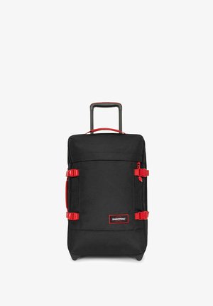 Black wheeled suitcase with red accents, featuring a telescopic handle, side straps, and smooth surface texture. Brand logo displayed prominently.