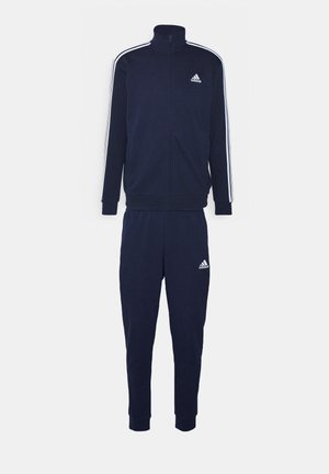 Granatowy dres sportowy wykonany z tkaniny, z zamkiem błyskawicznym, zawierający kurtkę z białymi paskami oraz dopasowane spodnie, obie części z logo Adidas.