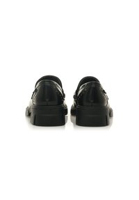 Scarpe in pelle nera con una finitura liscia, punta rotonda, tacco basso e borchie decorative sul retro. Il design presenta uno stile slip-on.