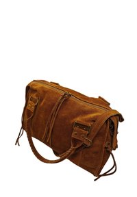 Sac à main en suède marron avec une fermeture éclair, deux poches latérales et des poignées tressées. Comprend des éléments en métal et des pompons décoratifs.