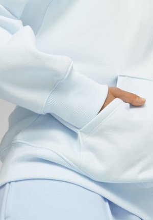 Sudadera azul claro con puños acanalados, una textura suave y un bolsillo delantero. Presenta costuras y un corte relajado para mayor comodidad.