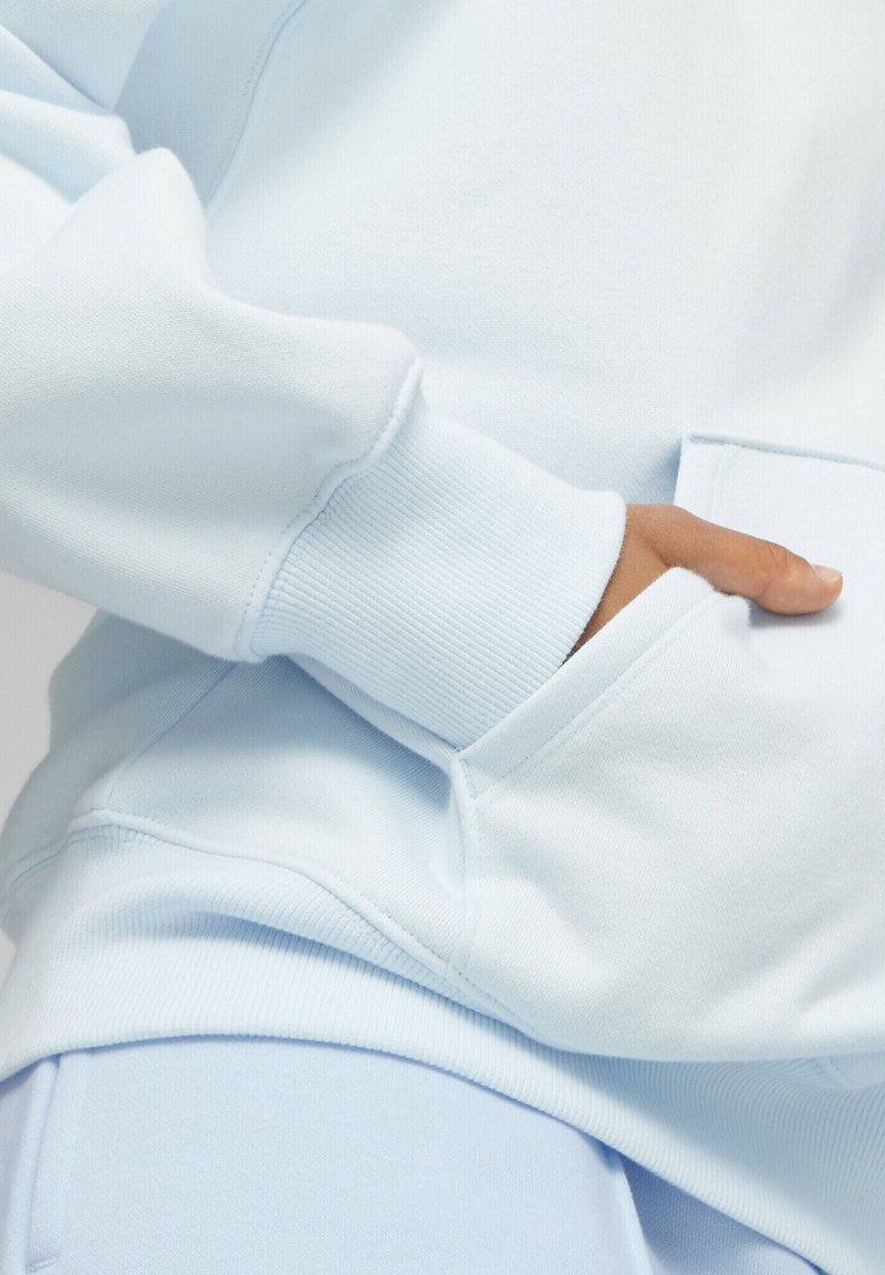 Lichtblauwe sweatshirt met ribbelmanchetten, een zachte textuur en een voorkantzak. Toont naden en heeft een ontspannen pasvorm voor comfort.