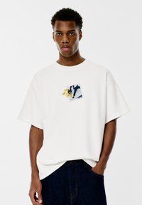 Weißes Baumwoll-T-Shirt mit kurzen Ärmeln, das einen Graf Druck auf der Brust zeigt, der eine Blumenanordnung und abstrakte Formen darstellt.
