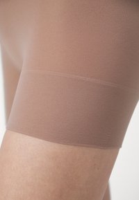 Beige seamless shorts with a smooth texture and soft fabric. The hem has a clean finish, resting just above the knee on a leg.