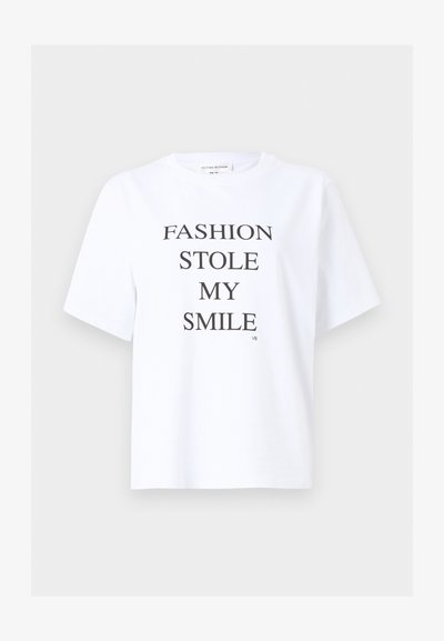 Λευκό κοντομάνικο μπλουζάκι με μαύρο κείμενο στο κέντρο που γράφει "FASHION STOLE MY SMILE" και μικρά αρχικά "VB" στο κάτω δεξί μέρος.
