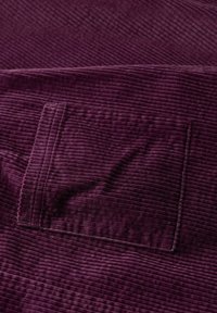 Violeta korduroja audums ar vertikālām rievām un plecu kabatas detaļu. Tekstūra izskatās mīksta un pūkaina, uzsverot materiāla dziļumu.